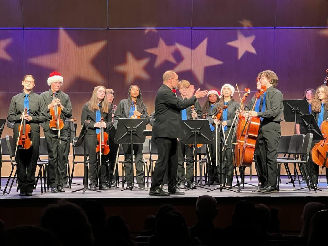 The Symphony Orchestra stands after their performance. Seniors are pictured wearing santa hats, a tradition for the Music Department. 